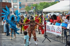 Children enjoy dancing with Sesame Flyers’ costumed masqueraders to the sounds of Eruption Steel Orchestra