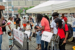 After several minutes in basics, it’s time for the steelpan ‘newbies’ to sound out their first tune, with tutors by their sides, clapping out the beat, while another in front keeps time on the cow bell